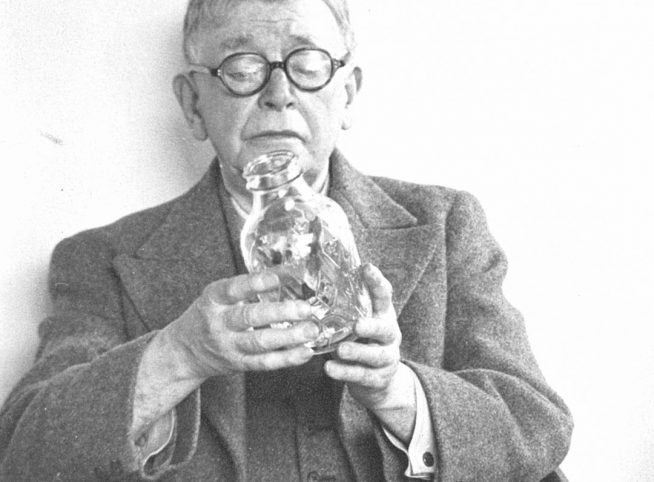 A black and white photo of a man holding a glass bottle made by Verallia